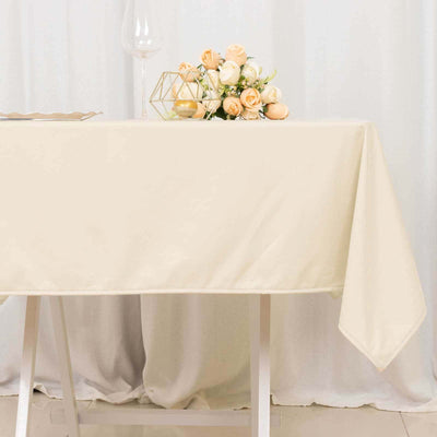 Cream tablecloth draped over a white table with a floral centerpiece.