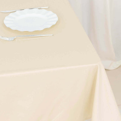 Elegant beige tablecloth with white plate and silver utensils.