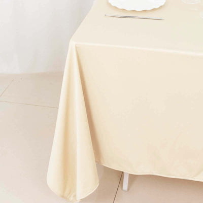 Beige tablecloth draped over a table with elegant dining setup.