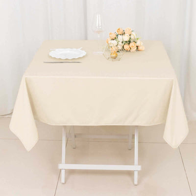 Beige tablecloth draped over a table set with a plate, glass, and floral centerpiece.