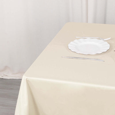 White scalloped plate on a beige tablecloth with cutlery.