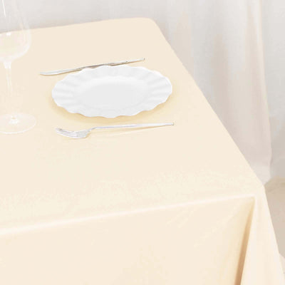 Elegant white plate on a soft beige tablecloth with utensils.