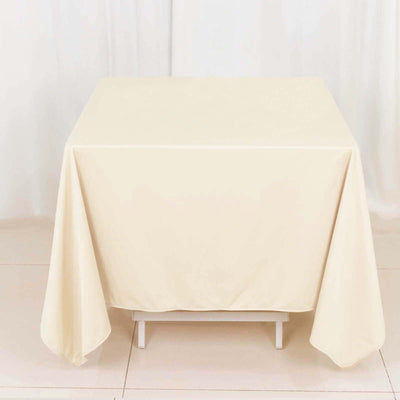 Cream tablecloth draped over a table on a plain backdrop.