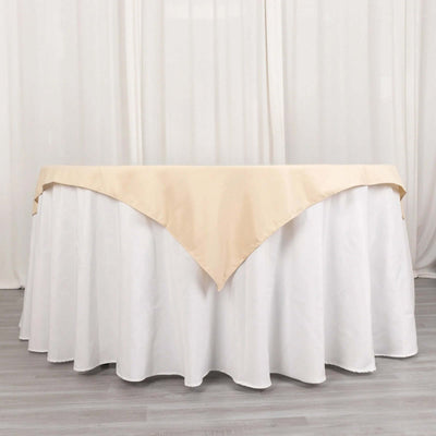 Beige table cover draped over a white tablecloth in a studio setting.