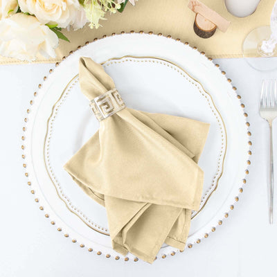 Elegant beige napkin with decorative ring on a white plate setting.