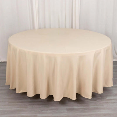 Round beige tablecloth on a circular table in a studio setting