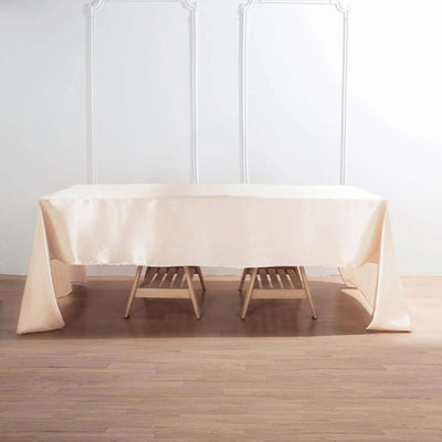 Beige tablecloth draped over a wooden table in a minimalist setting.