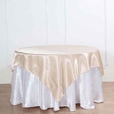 Round table with a beige satin tablecloth on a white background.