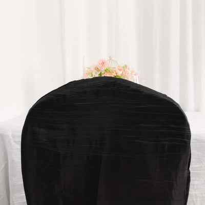 Black chair cover draped over a chair, with a decorative table in the background.