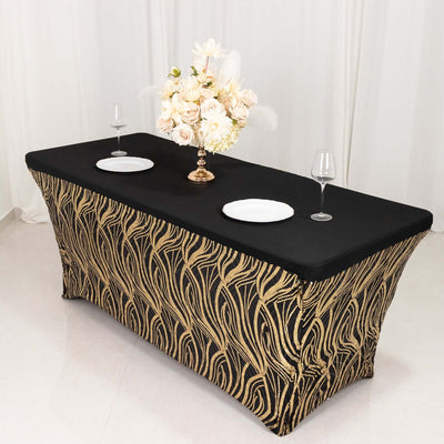 Elegant black tablecloth with gold design, set for dining with plates and floral centerpiece.