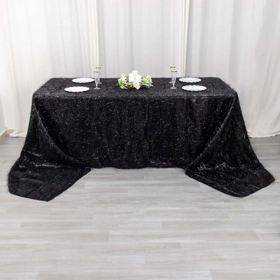 Black shimmering tablecloth draped over a table, styled with candles and plates.