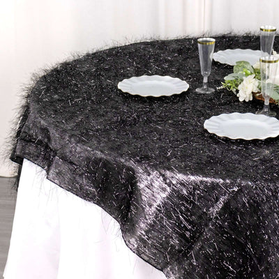 Black textured tablecloth with a fringed edge on a round table set for dining.
