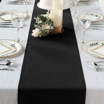 Elegant black table runner on a dining table set with floral plates and candles.