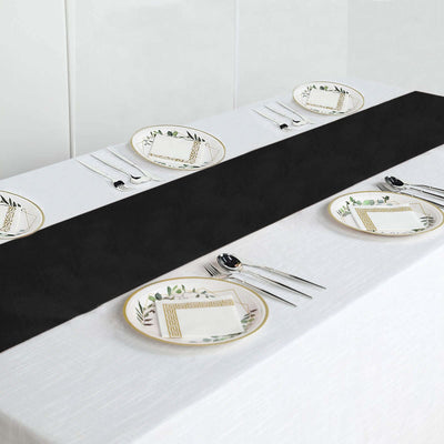 Black table runner on a white table with decorative plates and cutlery.