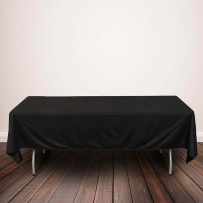 Black tablecloth draped over a folding table on a wooden floor.