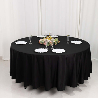 Round black table with white plates and elegant centerpieces for dining.