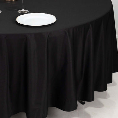 Round black tablecloth draping elegantly over a table with a white plate.