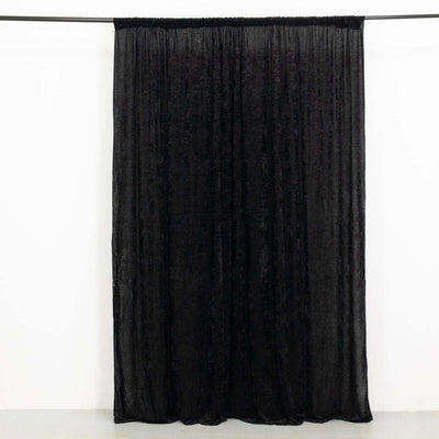 Black sheer curtain hanging against a plain background.