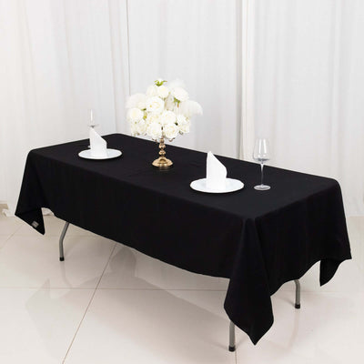 Elegant black tablecloth set for dining with flowers and tableware.