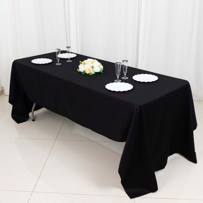 Elegant black table setup with floral centerpiece and white plates.