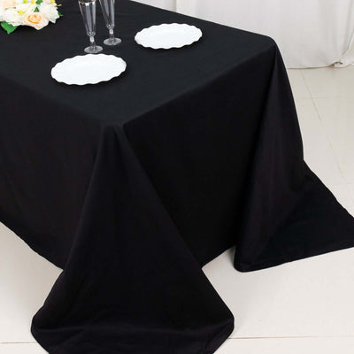 Black tablecloth draped elegantly over a table with white plates and decorative flowers.