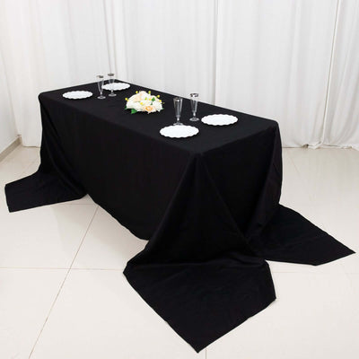 Black tablecloth set on a table with plates and glasses for dining.