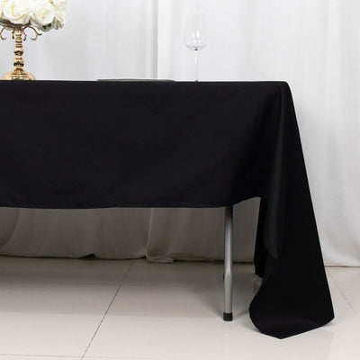 Black tablecloth draped elegantly over a table with a glass and floral centerpiece.