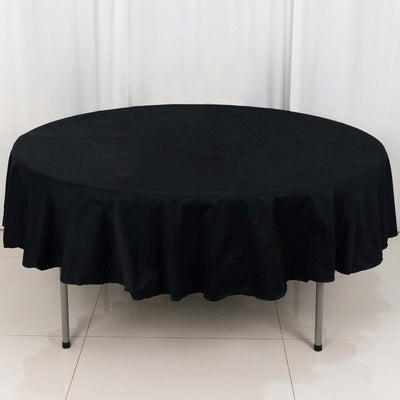 Black round tablecloth with a ruffled edge on a table.