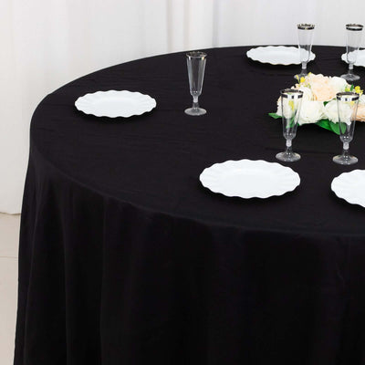 Elegant black table setting with white plates and floral centerpiece.