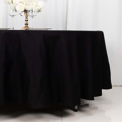 Black tablecloth draping over a table with a floral centerpiece and glassware.
