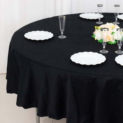 Black tablecloth with white plates and floral centerpiece on a round table.