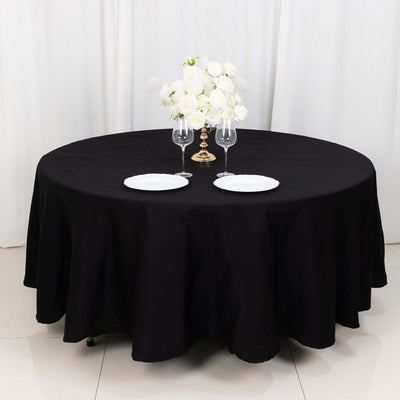 Round black tablecloth with white plates and floral centerpiece.