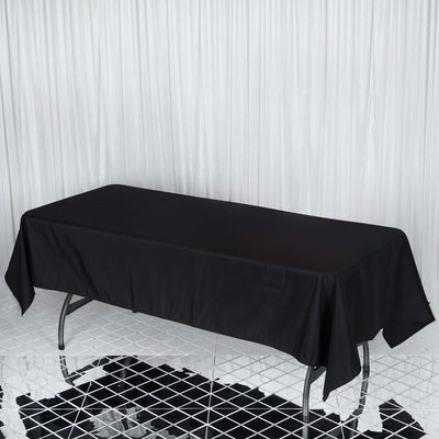 Black tablecloth draped over a rectangular table on a reflective floor.