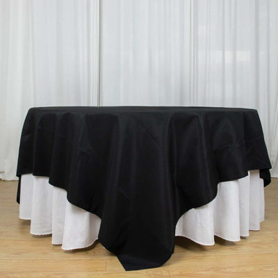 Black tablecloth draped over a round table with a white undercloth.