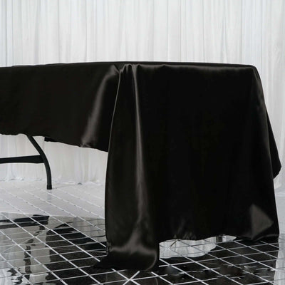 Black satin tablecloth draped elegantly over a table in a studio setting.