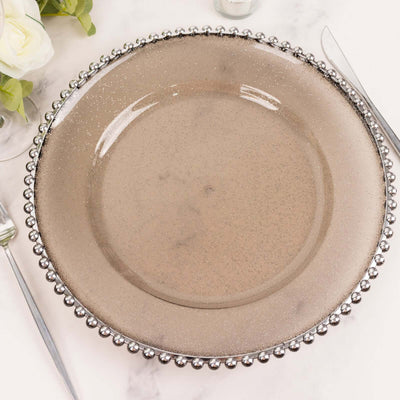 Elegant round glass charger plate with beaded rim, perfect for table settings.