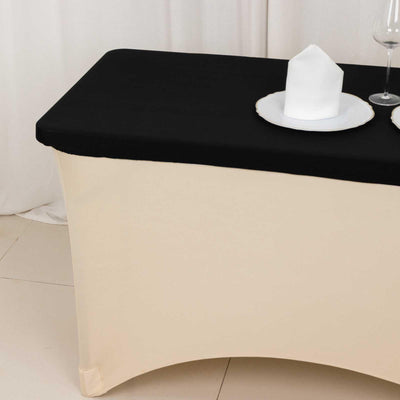 Black tablecloth draped over a cream-colored table with plates and a candle.