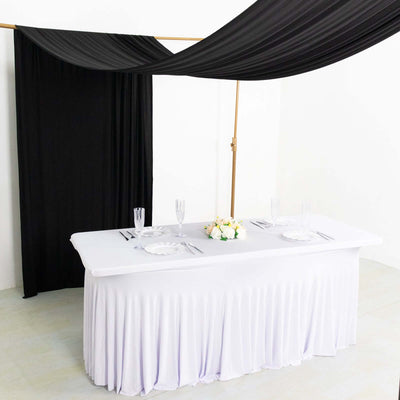Elegant white table setup with black drapery and floral centerpiece.