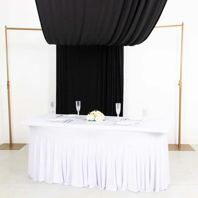 Elegant wedding table setup with white draping and black backdrop.