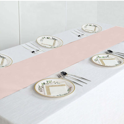 Elegant pink table runner on a white table setting with decorative plates and cutlery.