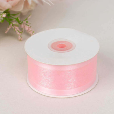 Pink satin ribbon spool for crafting and decorating.