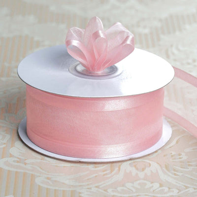 Pink satin ribbon on a spool with a decorative bow