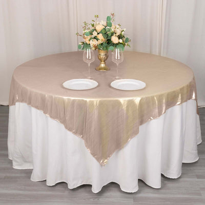 Elegant round table set with gold tablecloth, floral centerpiece, and dinnerware.
