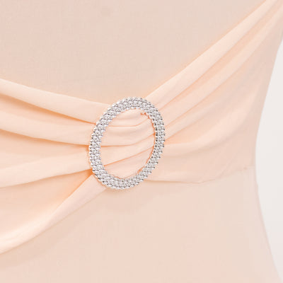 Elegant peach dress with a sparkling rhinestone brooch detail.