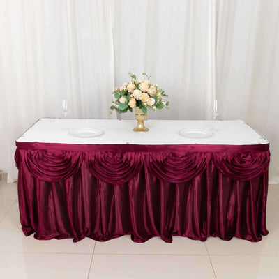 Elegant burgundy tablecloth with pleated design, centerpiece, and dinnerware setup.