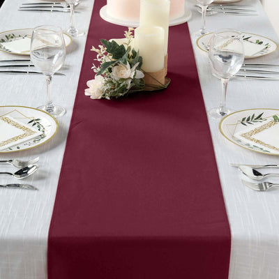 Burgundy table runner on a dining table set for a formal meal.