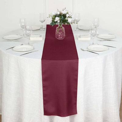 Burgundy table runner on a round table set for dining
