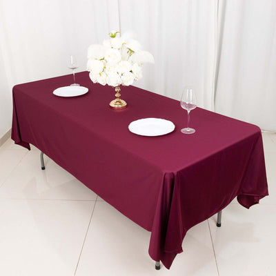 Elegant burgundy tablecloth draped over a table with floral centerpiece and glassware.