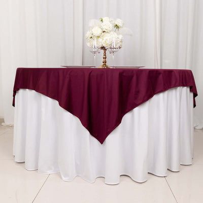 Burgundy tablecloth draped over a white table with floral centerpiece