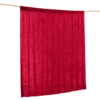 Red velvet curtain hanging on a rod against a plain background.